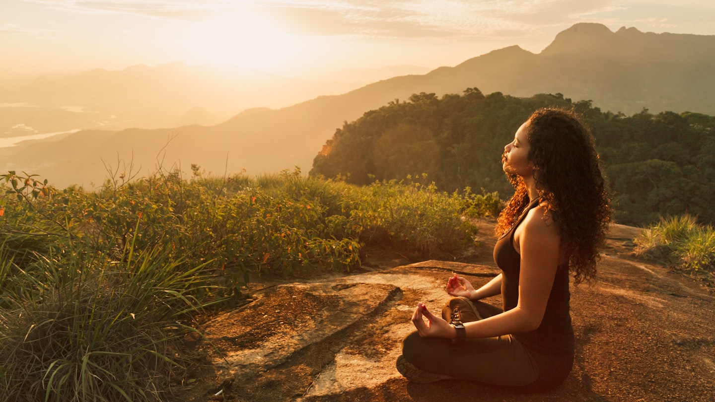 Young woman meditating on a mountain top in Rio de Janeiro.