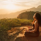 Young woman meditating on a mountain top in Rio de Janeiro.