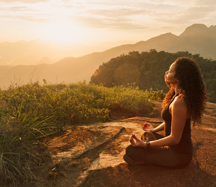 Young woman meditating on a mountain top in Rio de Janeiro.