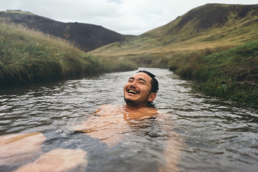 Man soaking in natural hot spring surrounded by nature in Iceland