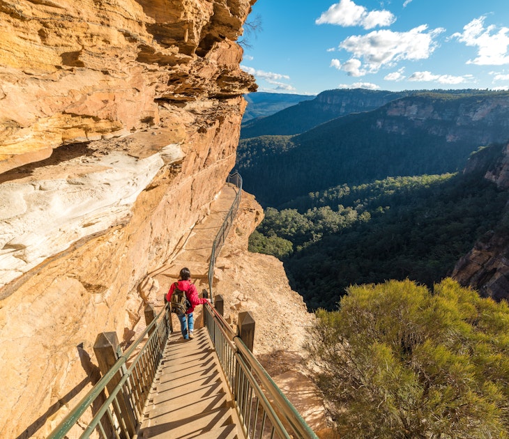 Mountain landscape with a woman hiking, going downstairs mountain track. Wentworth Falls, Blue Mountains National Park, Australia