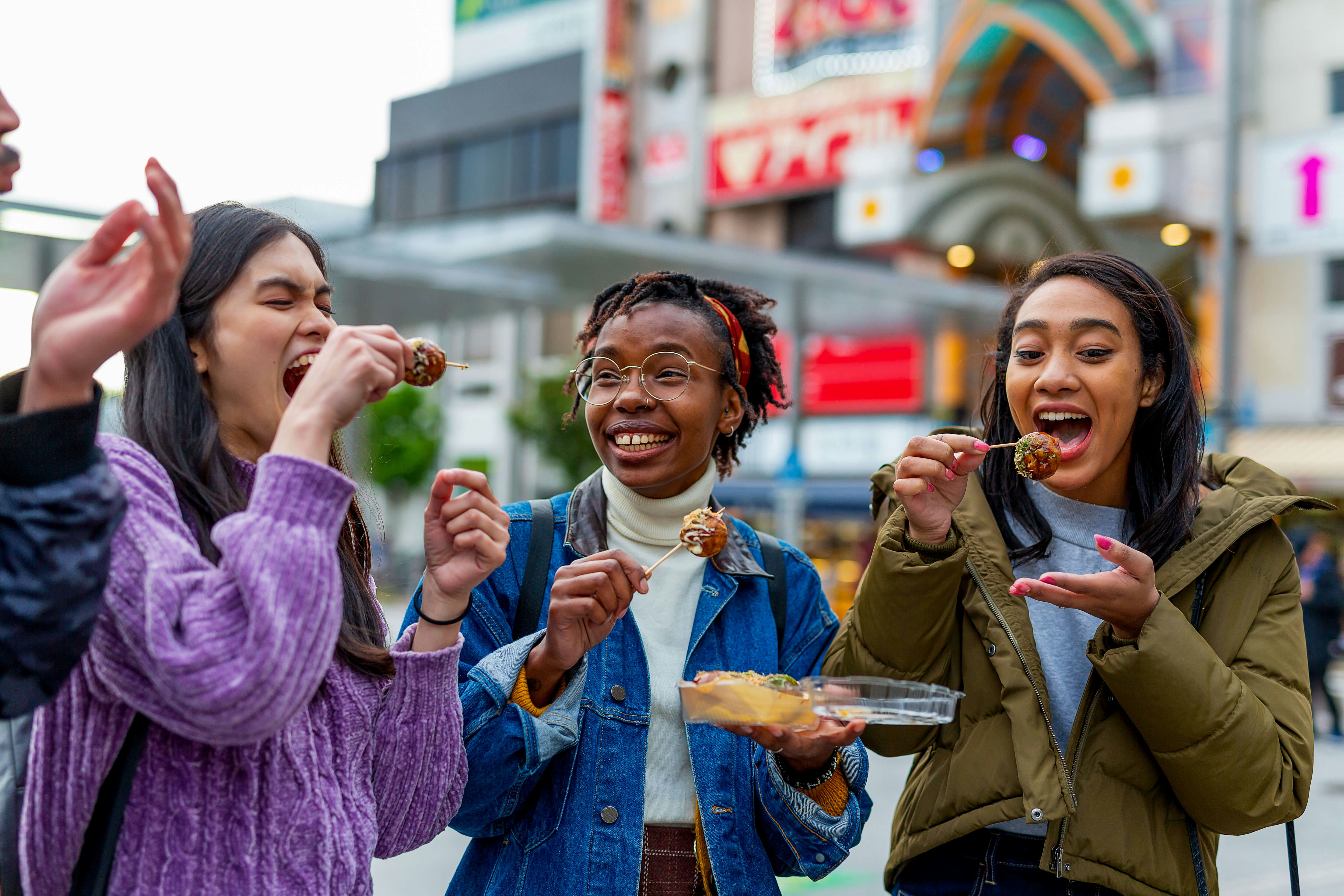 Group of Friends Eating Take Away Food on the Street in Tokyo Japan Davidf GettyImages-1166370053 rfc.jpg