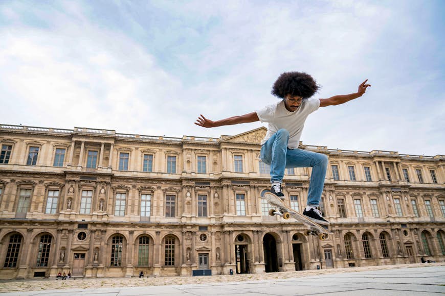 A man performs a trick on a skateboard in a square in Paris