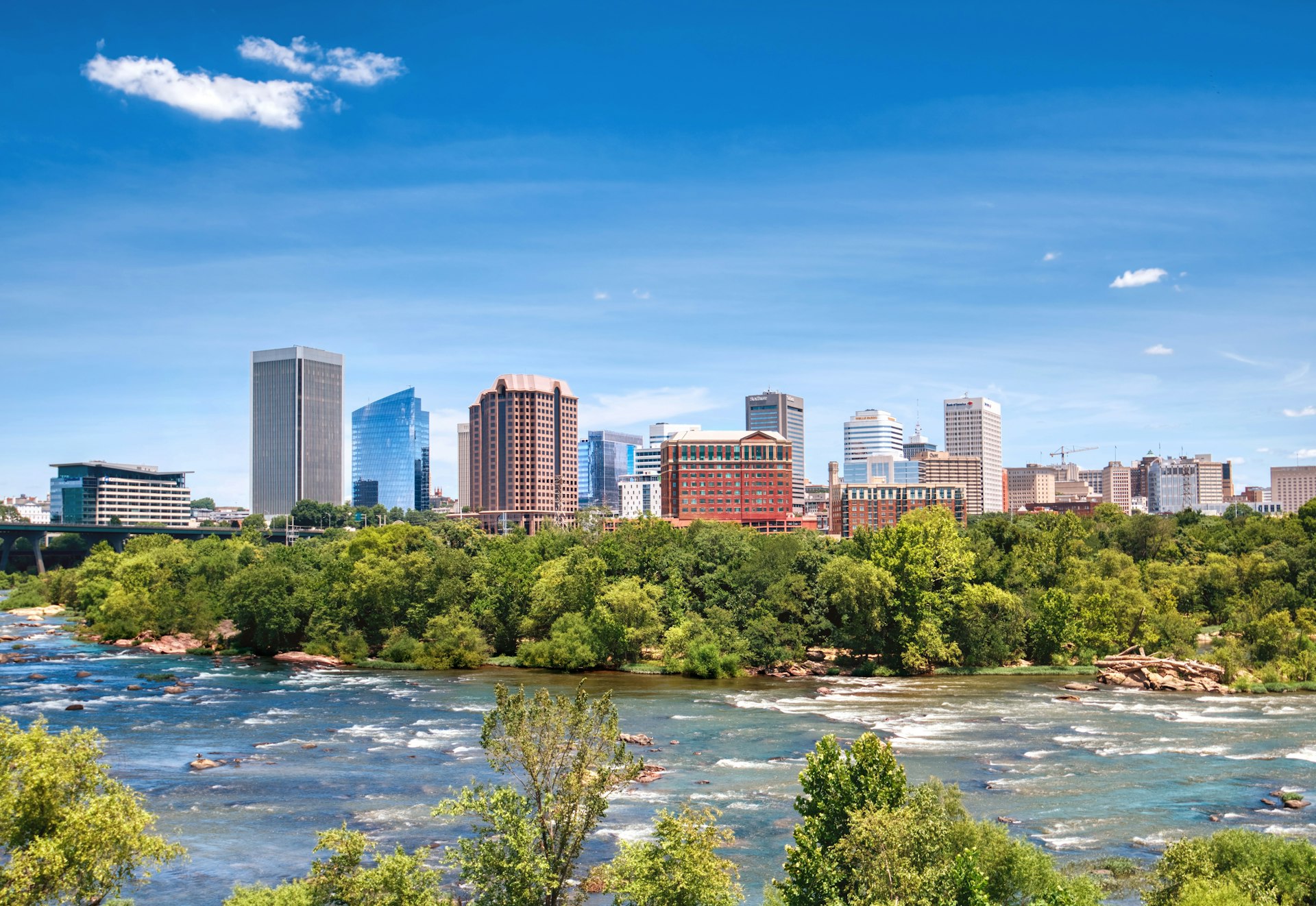 A view of the skyline of Richmond, Virginia, with the wide James River running in front of it.