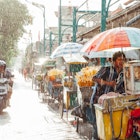 Ubud, Indonesia - March 08, 2016: Indonesian food vendor hides from the rain under the umbrella of his stall on the street of Kuta, Bali, Indonesia on March 08, 2016