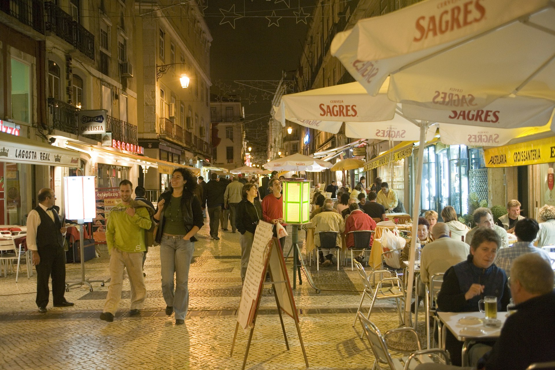 People walking beside open-air restaurants in Baixa