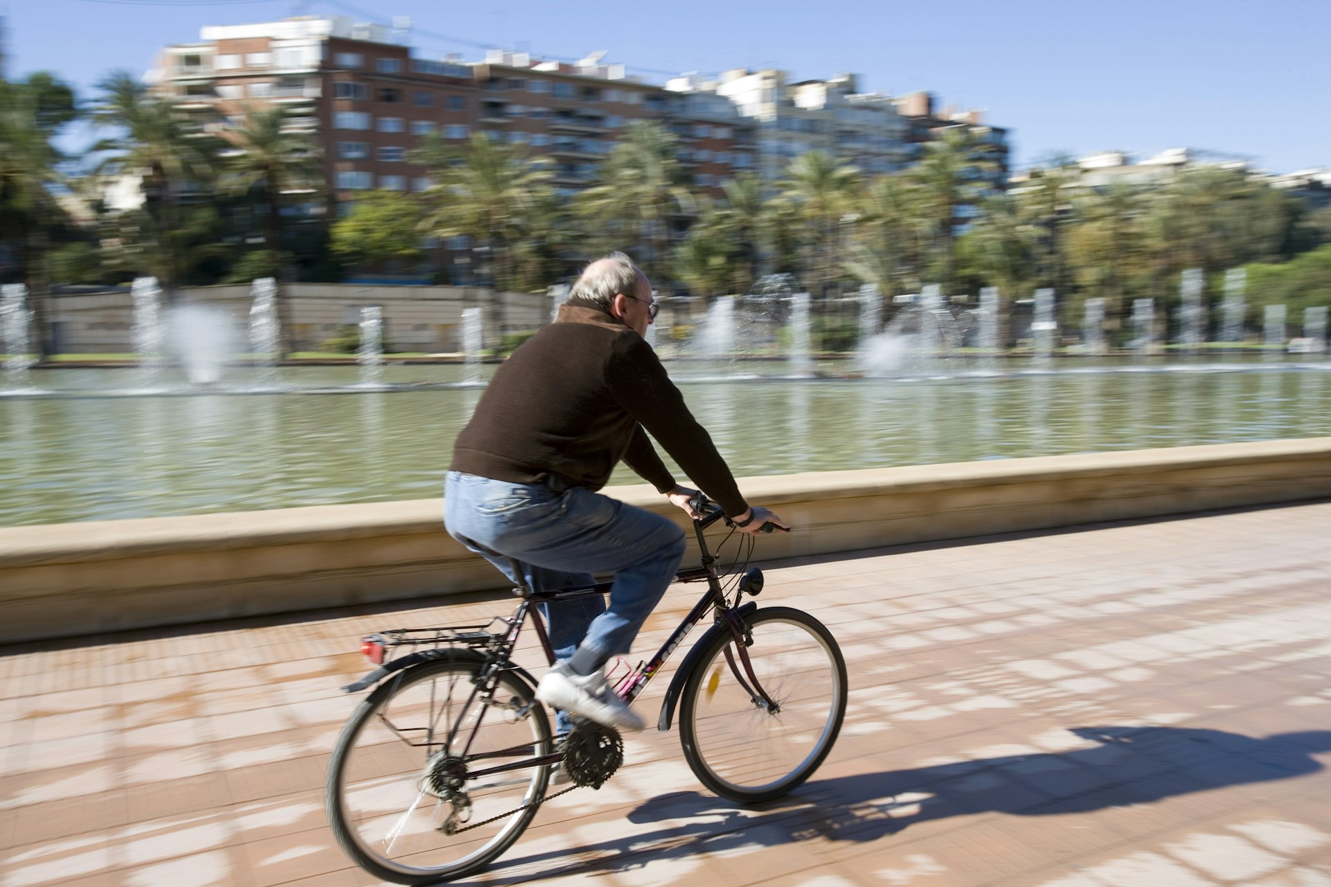 A man riding his bike in Jardines del Turia against a blurry background