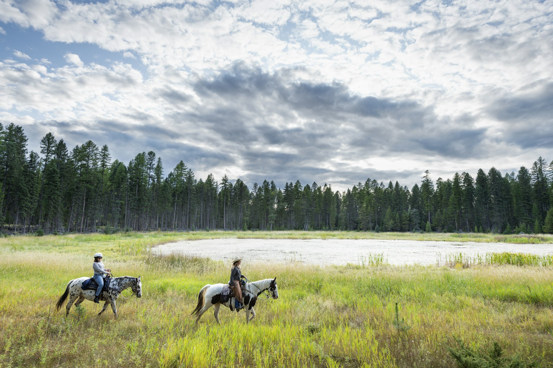 Two men riding horses in a forest clearing in Montana