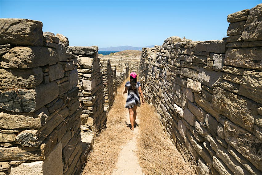 Μόλις φτάσετε στον προορισμό σας, ο καλύτερος τρόπος για να μετακινηθείτε είναι συχνά με τα πόδια Γυναίκα που περπατά κατά μήκος των ερειπίων της Δήλου
