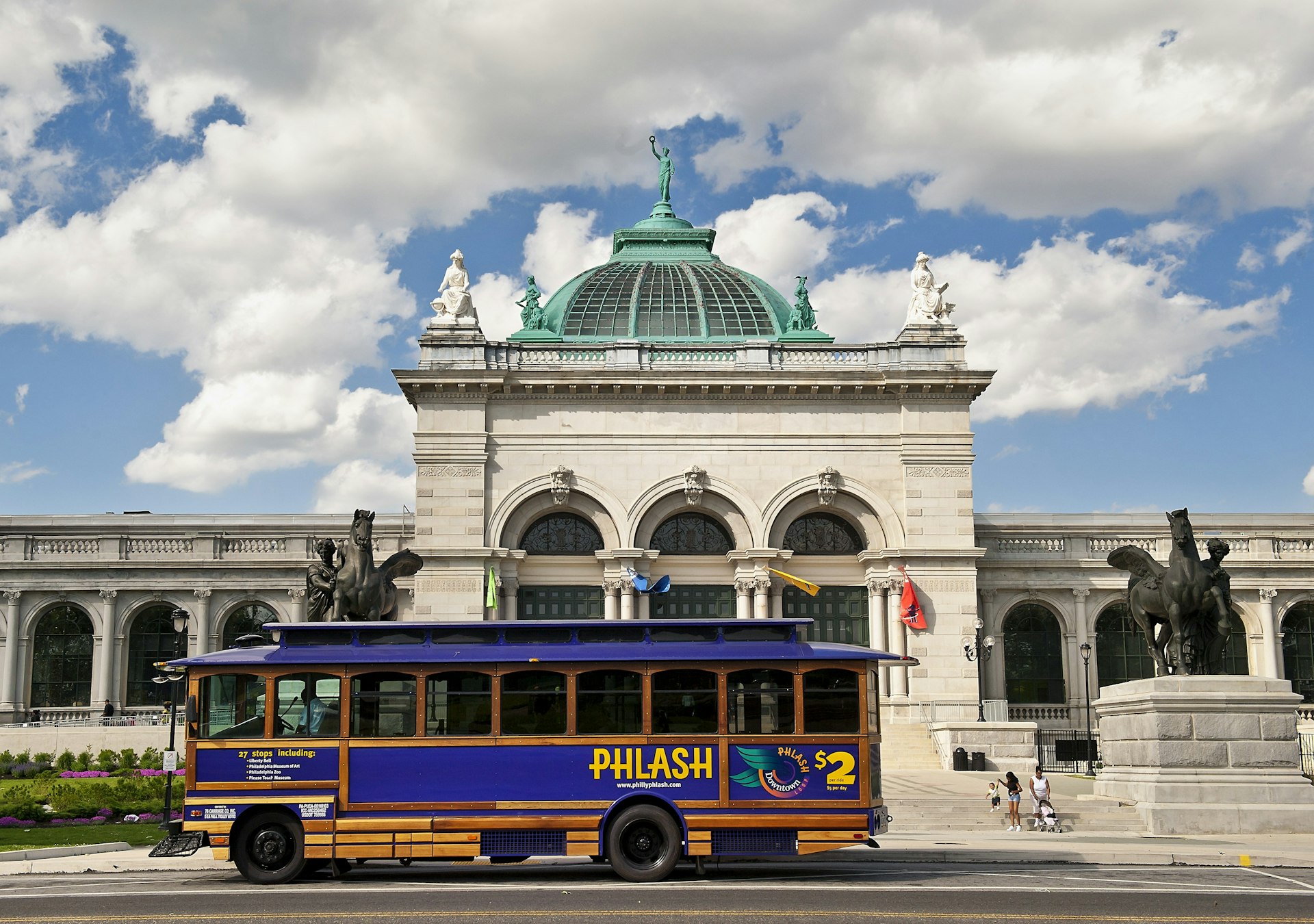 The purple PhillyPHLASH trolly bus rolls past the Please Touch museum on a cloudy day in Philadelphia. 