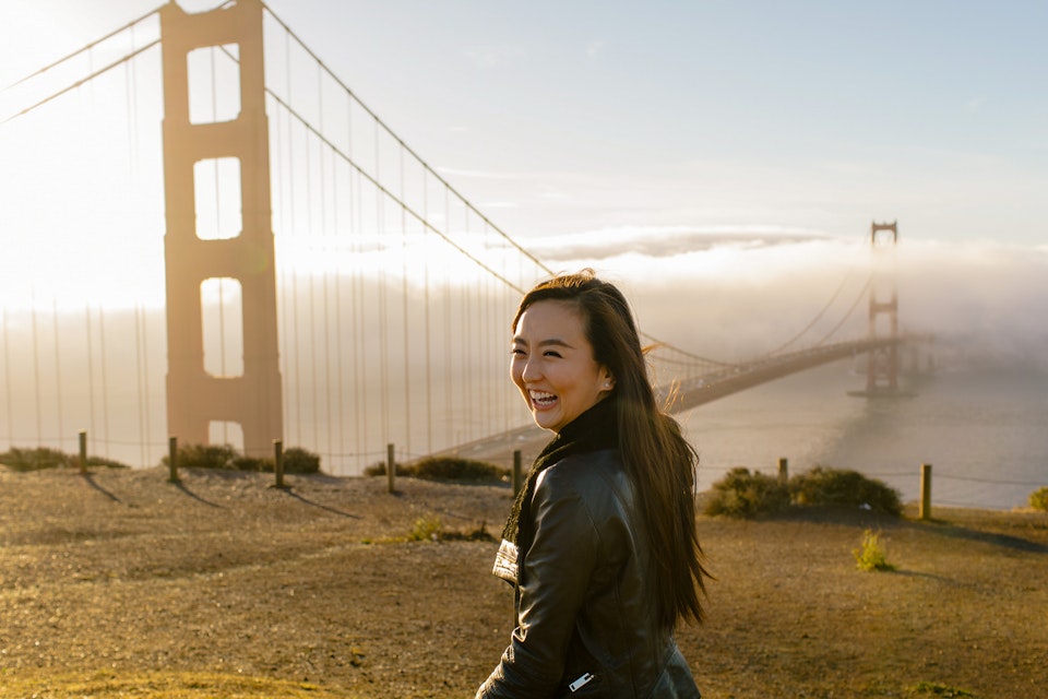 Woman in front of Golden Gate Bridge at sunrise in San Francisco