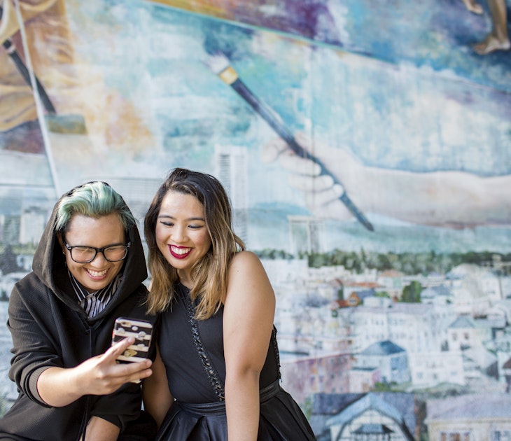 Smiling Asian women posing for cell phone selfie
