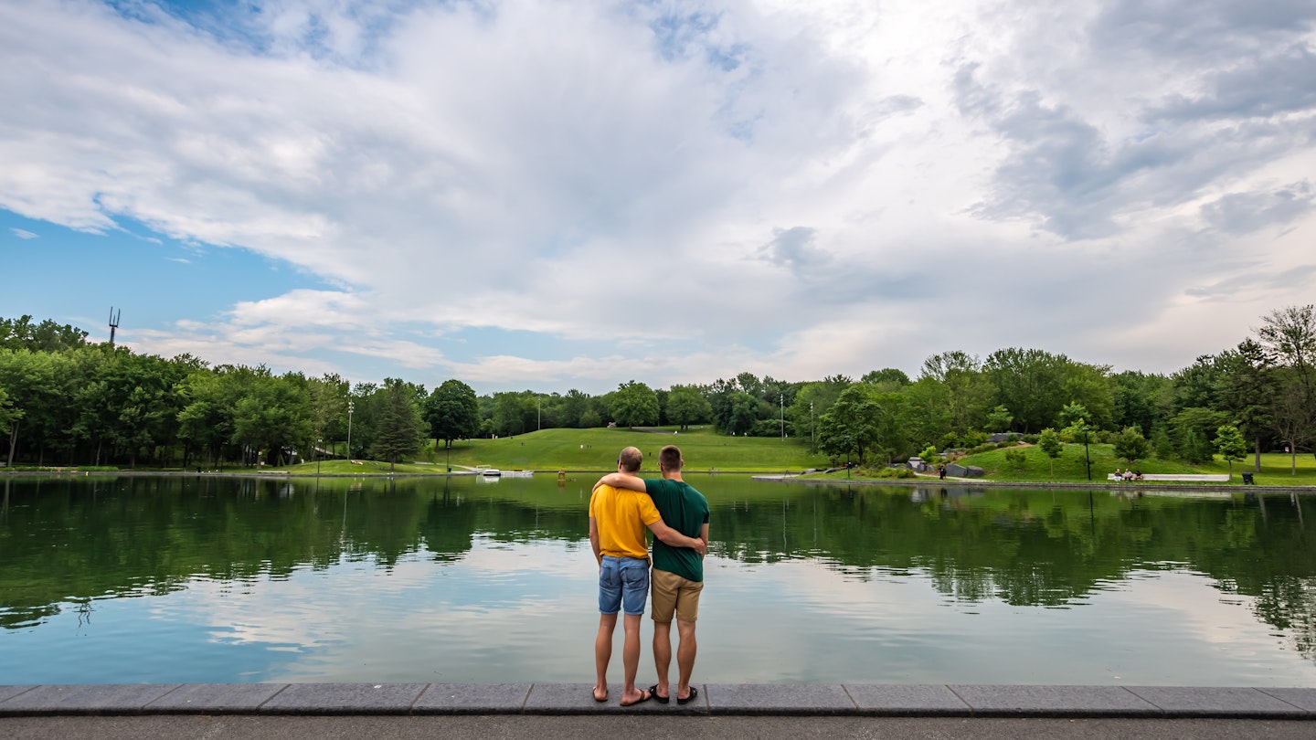 Couple embracing each other while visiting the Beaver lake on the Mount Royal, Montreal, during summer.