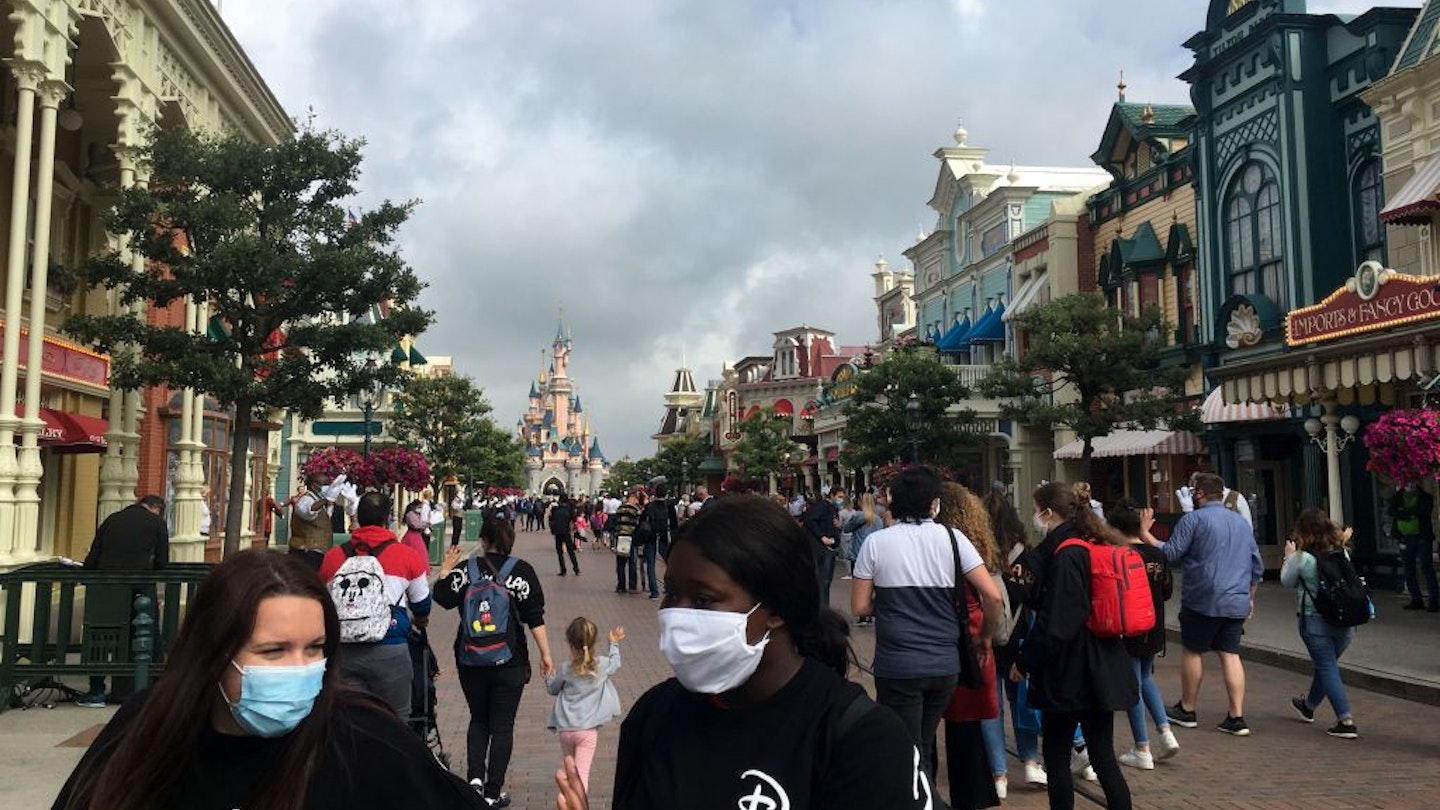 Visitors wearing protective face masks, walk down the Main Street of Disneyland Paris in Marne-la-Vallee, near Paris, on July 15, 2020, as Disneyland Paris begins phased reopening after months-closure aimed at stemming the spread of the novel coronavirus (COVID-19). (Photo by Aurelia MOUSSLY / AFP) (Photo by AURELIA MOUSSLY/AFP via Getty Images)