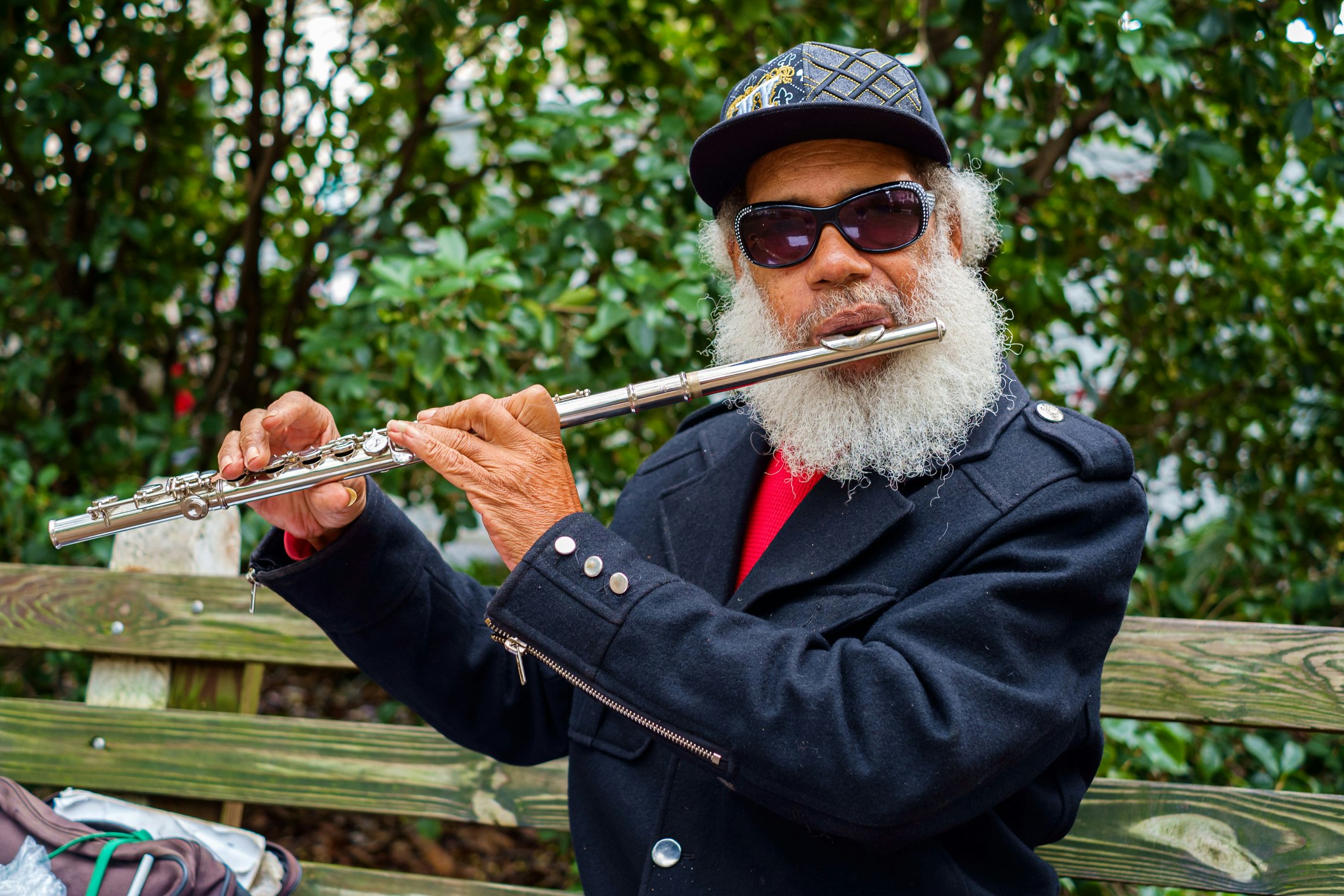 A black musician plays the flute outside in a leafy square in Savannah's historic district