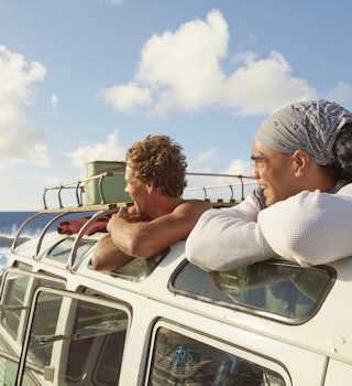 Two men look at the beach from inside a van