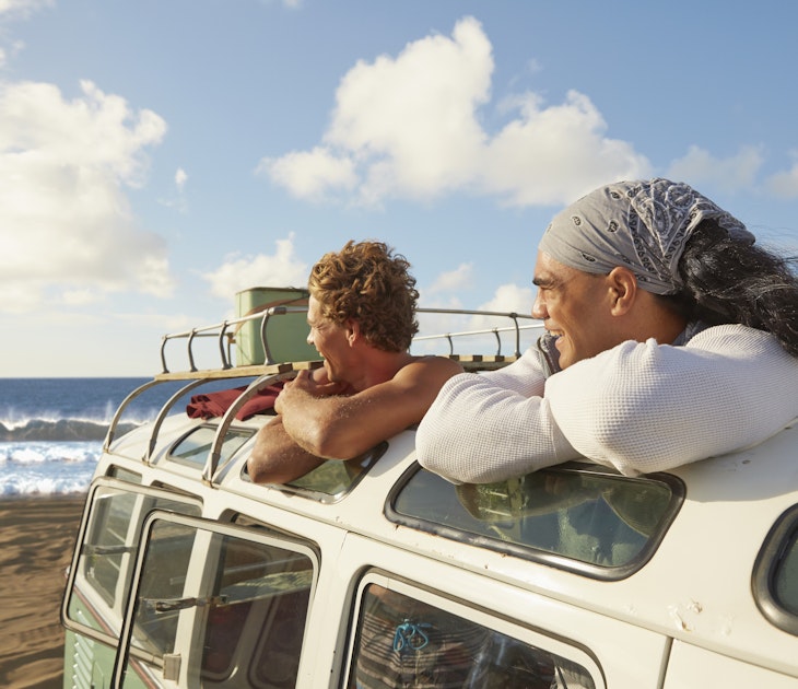 Two men look at the beach from inside a van