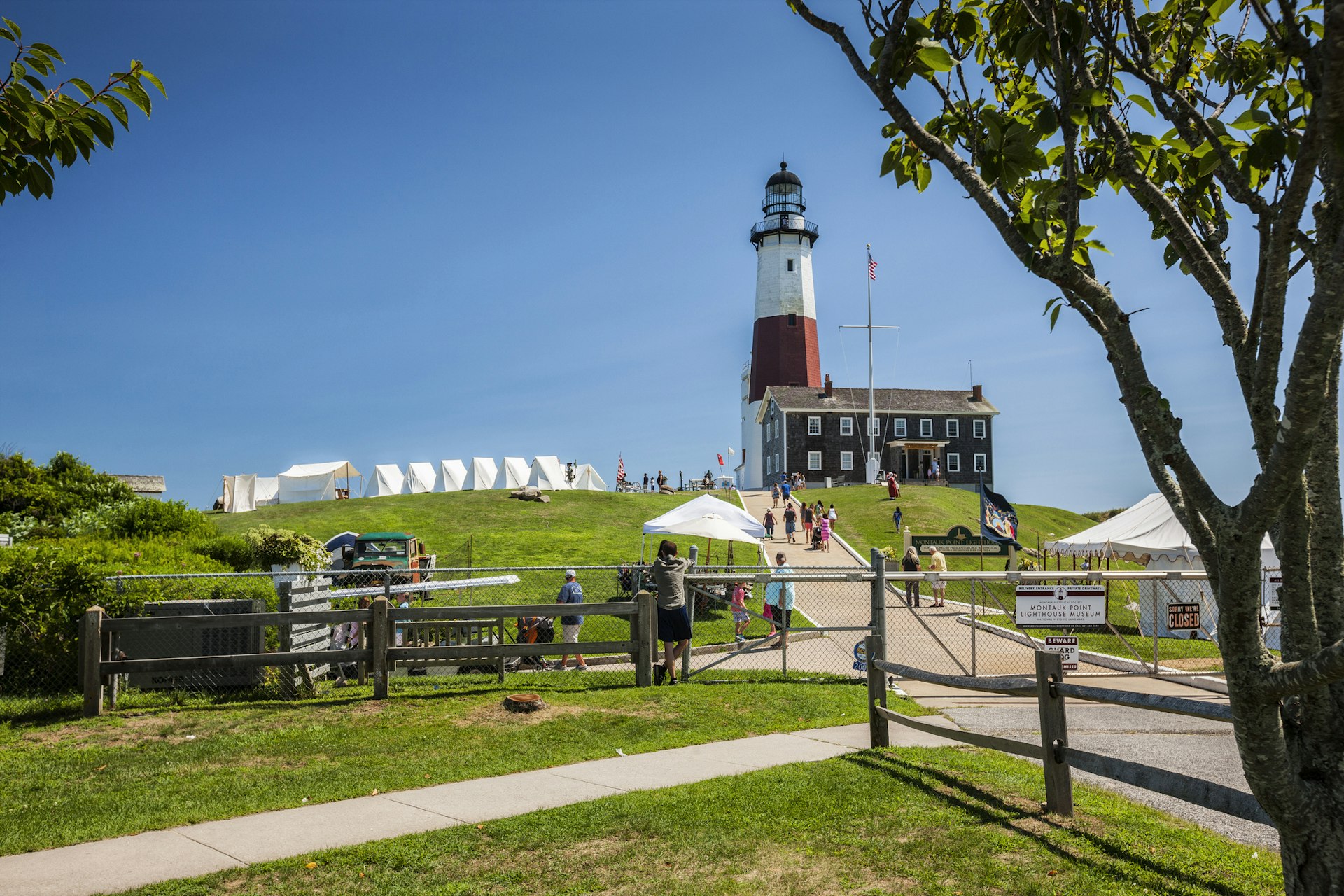 A view upward to Montauk point Lighthouse with a clear blue sky behind it.