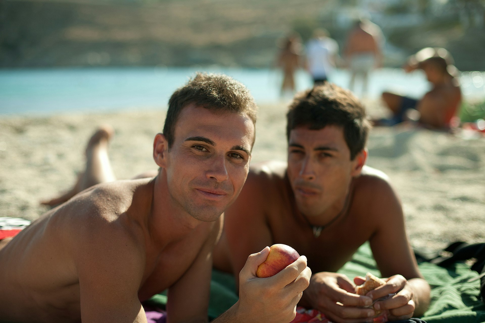 Two men lying on beach towels on a beach in Mykonos