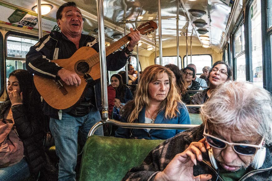 People on bus being serenaded by singer with guitar, producing mixed reactions, in Central Valparaiso, UNESCO World Heritage Site, Chile
