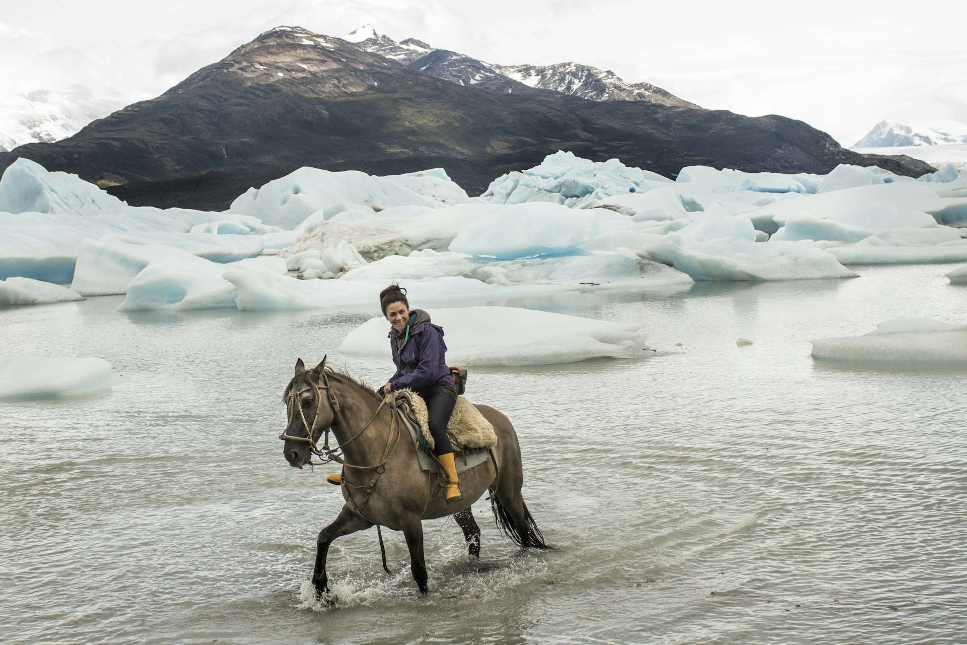 Chilean woman rides a horse in glacial lake