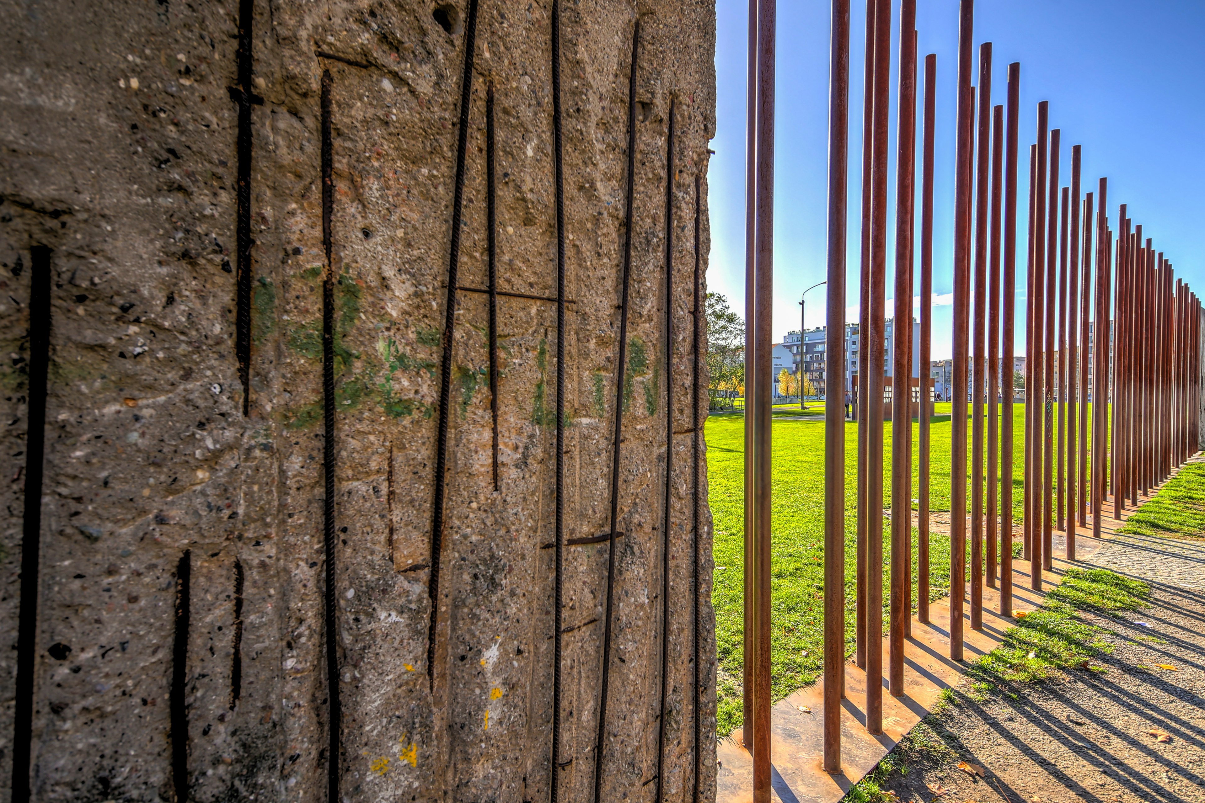 A close-up of a section of wall which gives way to a series of metal supports embedded in the ground