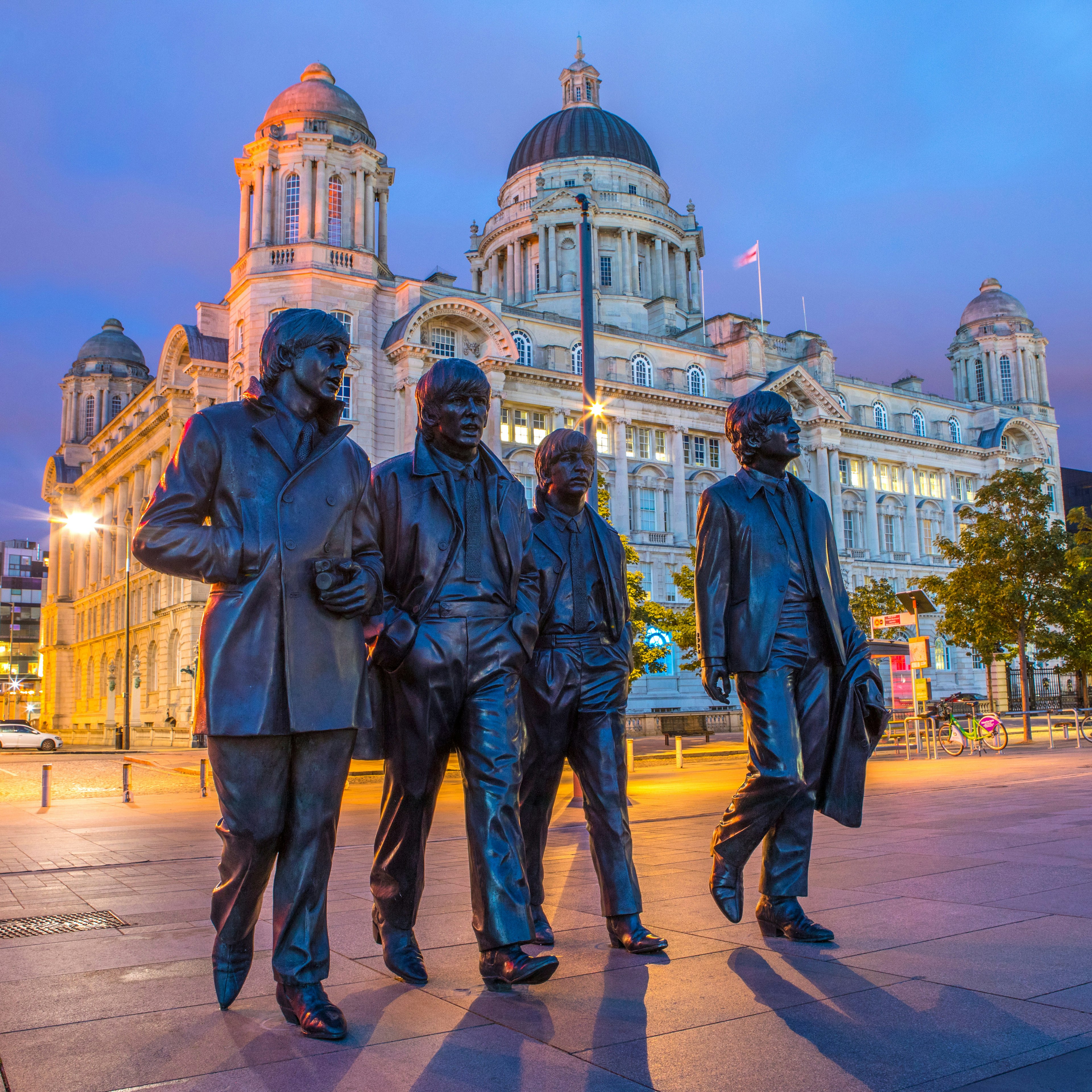 Statue of The Beatles at Pier Head in Liverpool at night.