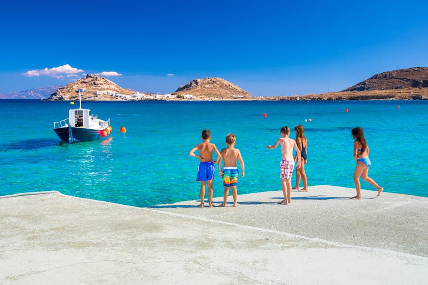 Group of kids preparing to jump into the sea from the pier at Kalafati Beach on Mykonos in Greece