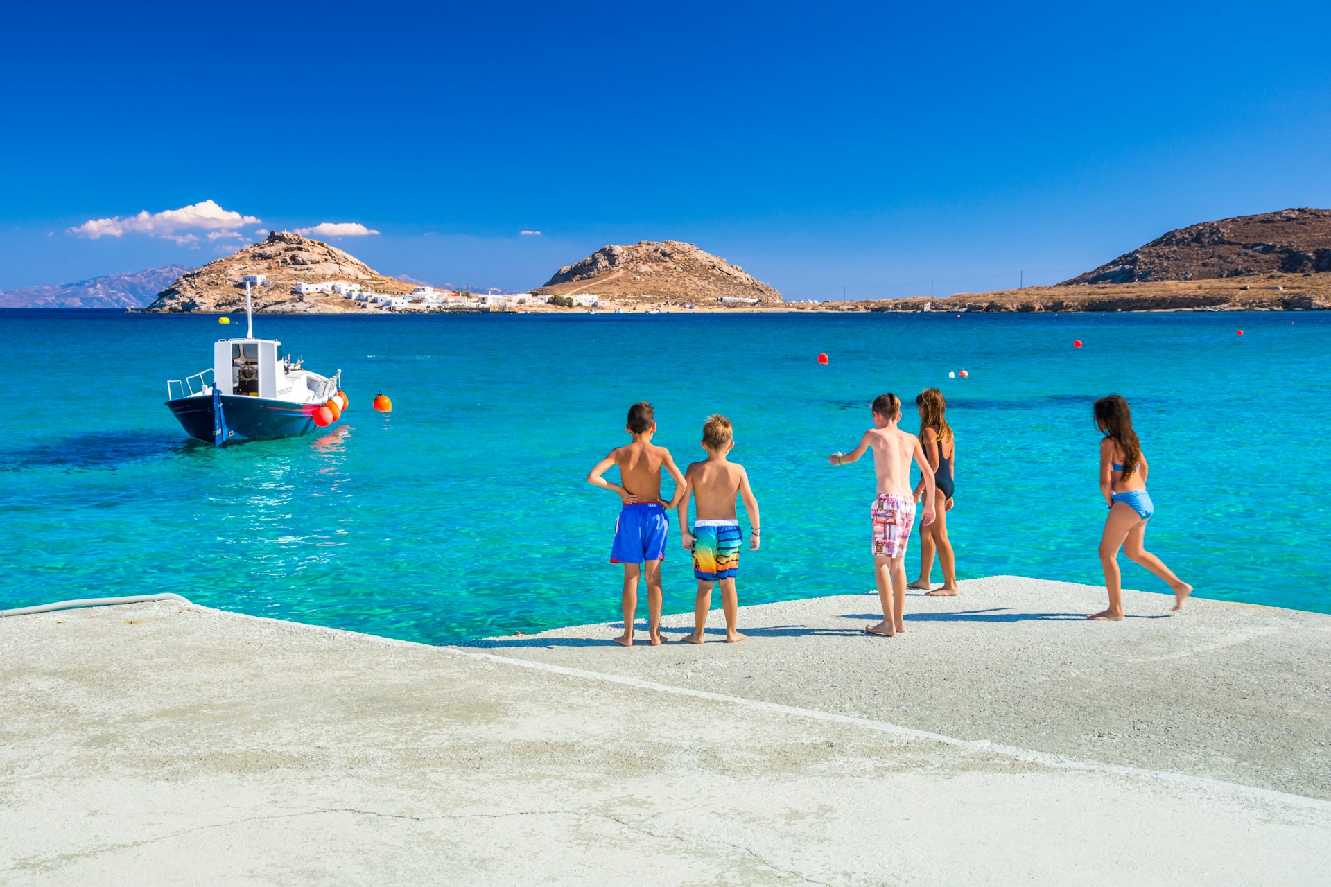 Group of kids preparing to jump into the sea from the pier at Kalafati Beach on Mykonos island