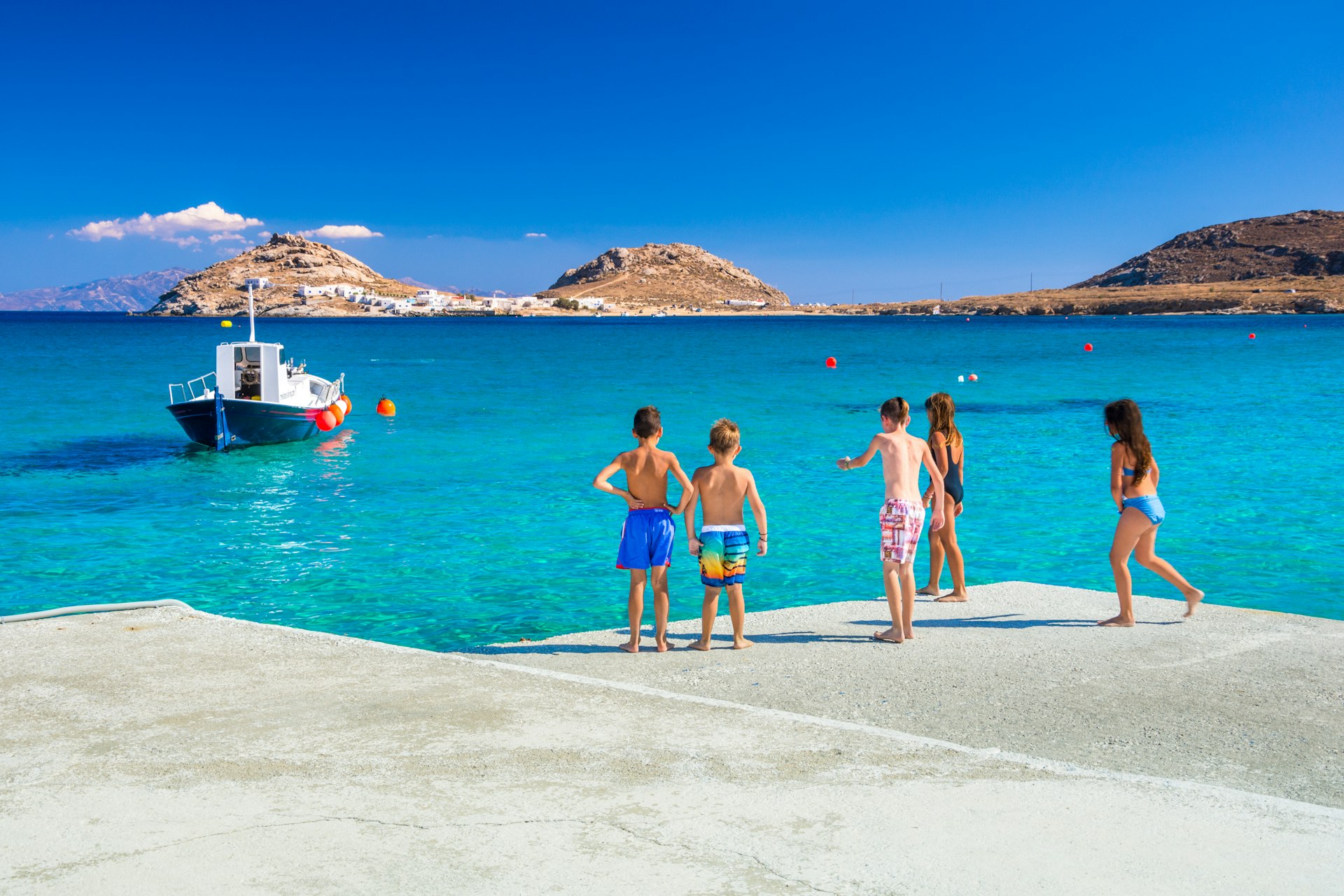 Group of kids preparing to jump into the sea from the pier at Kalafati Beach on Mykonos in Greece