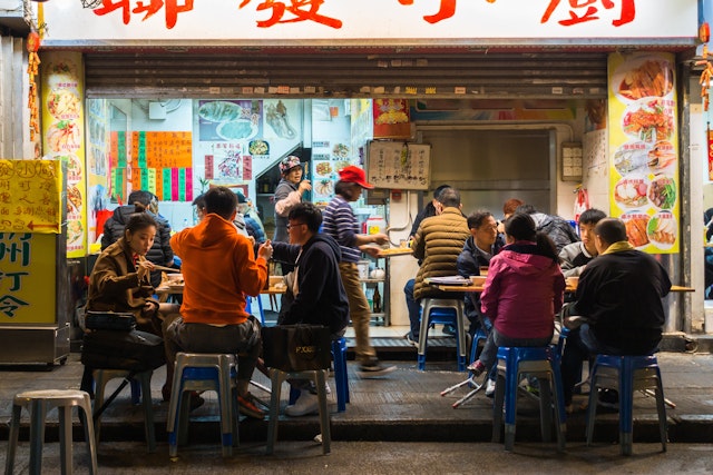 Street scene with local people dine at a street vendor in Mong Kok area. Hong Kong