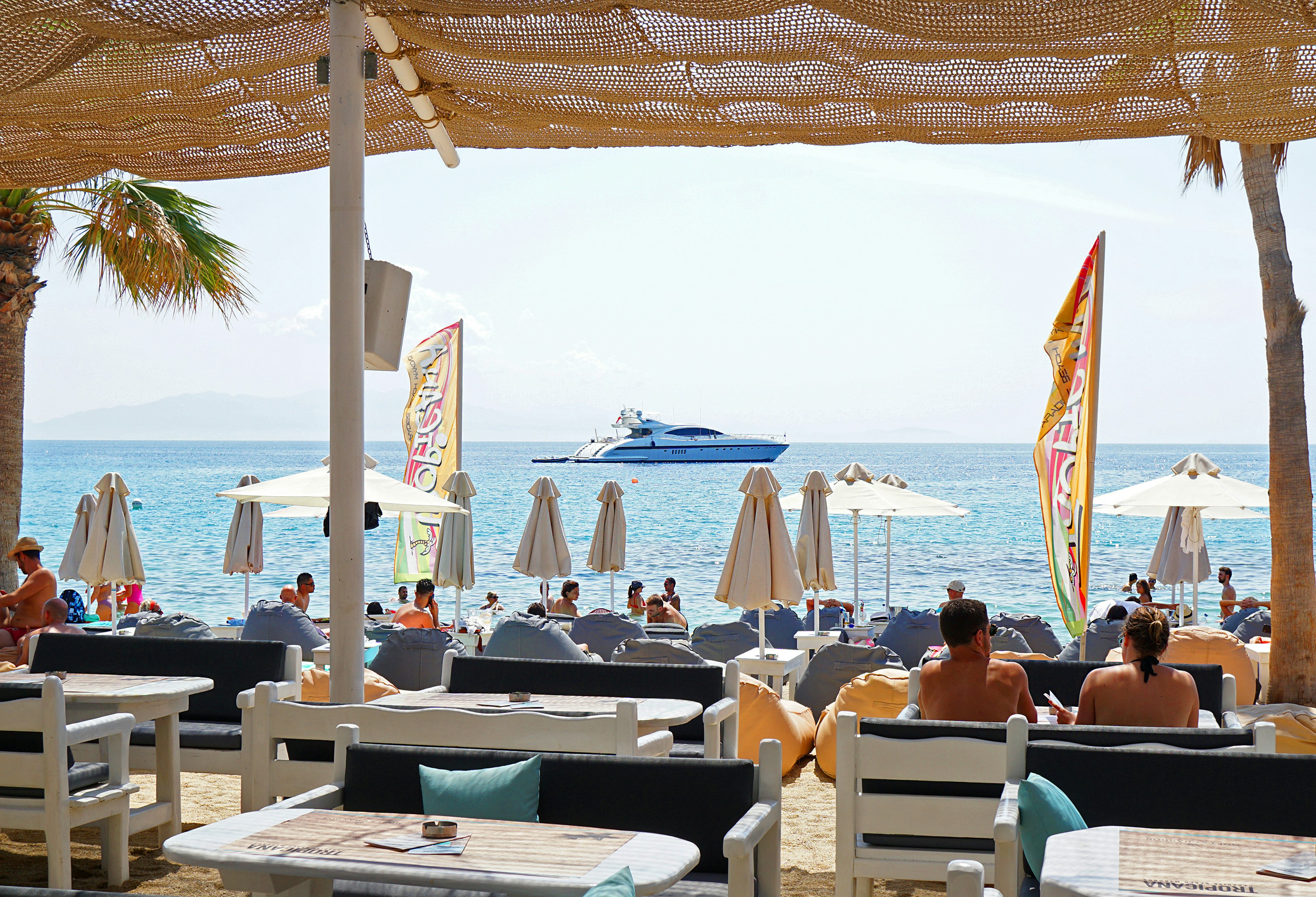 People seated at tables on Paradise Beach, looking out at the ocean