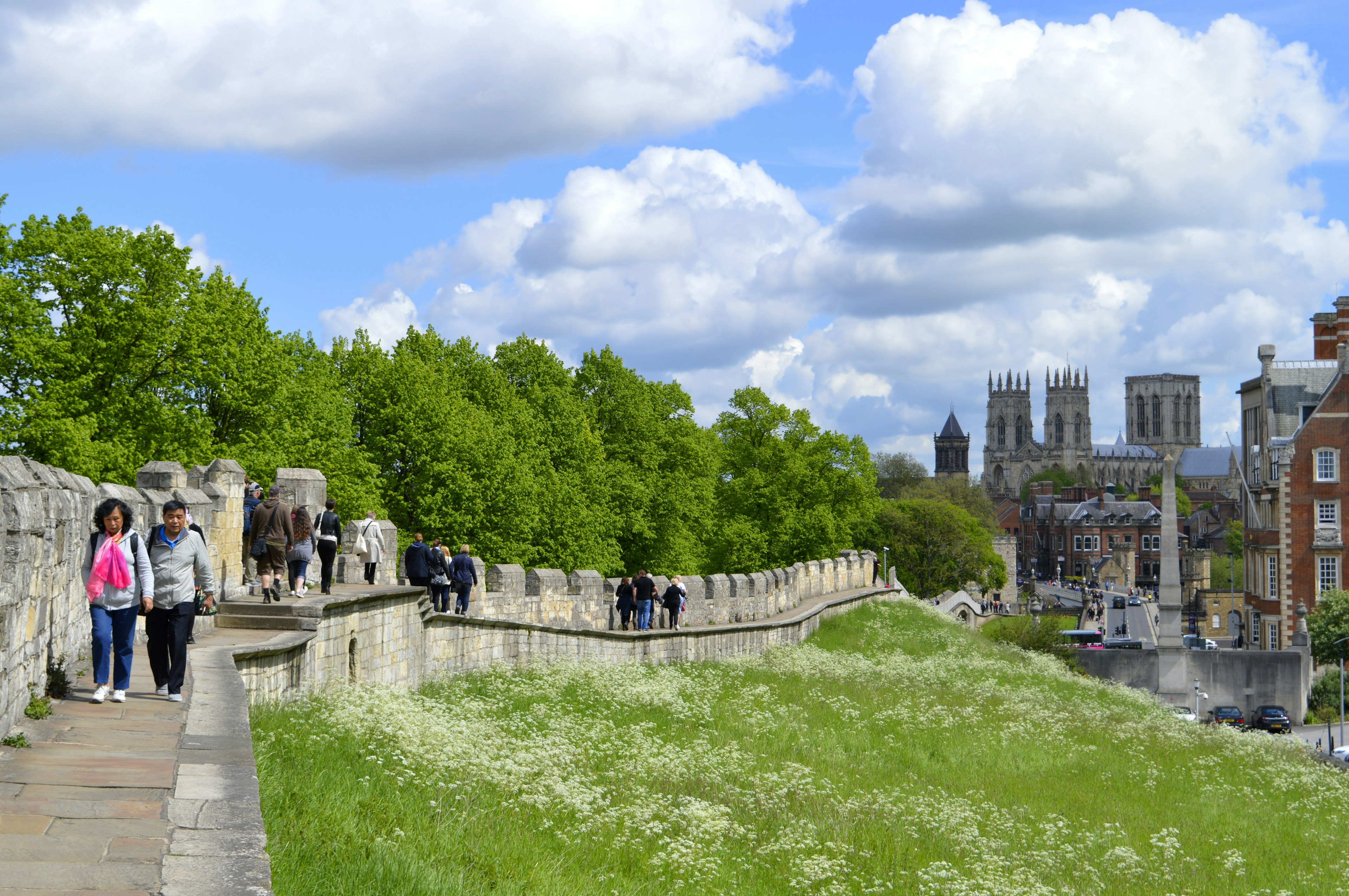 Tourists walking along York City Roman wall surrounding the City