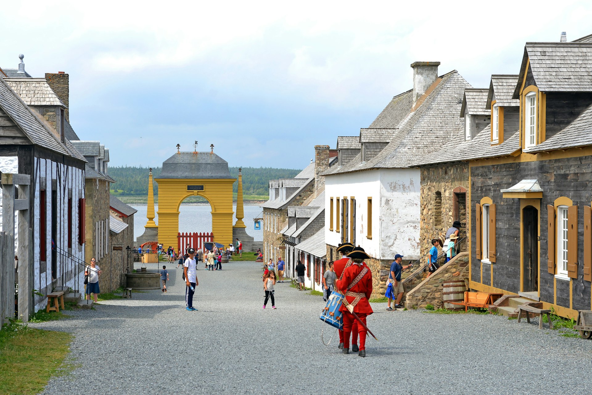 Tourists walk alongside people dressed as soldiers from the 1700s in historic street 