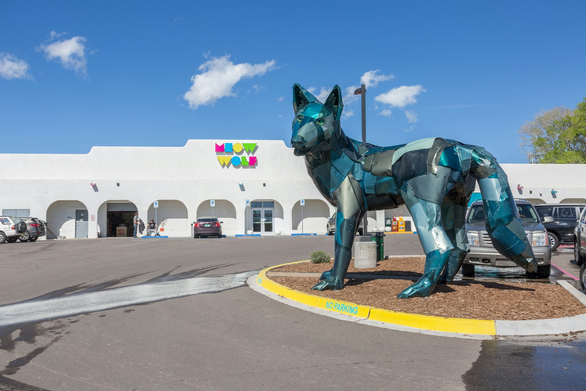 Meow Wolf interactive art gallery, as seen from the outside. The gallery is a large, white building, with a large wolf statue outside.