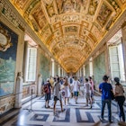 August, 2017: Visitors walk under frescoes in a hallway at the Vatican Museum.