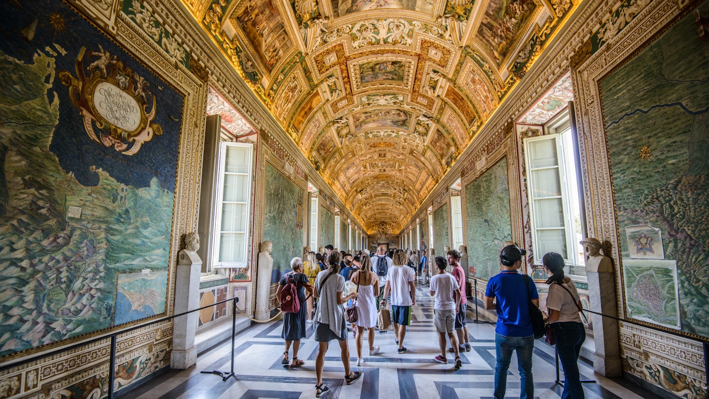 August, 2017: Visitors walk under frescoes in a hallway at the Vatican Museum.