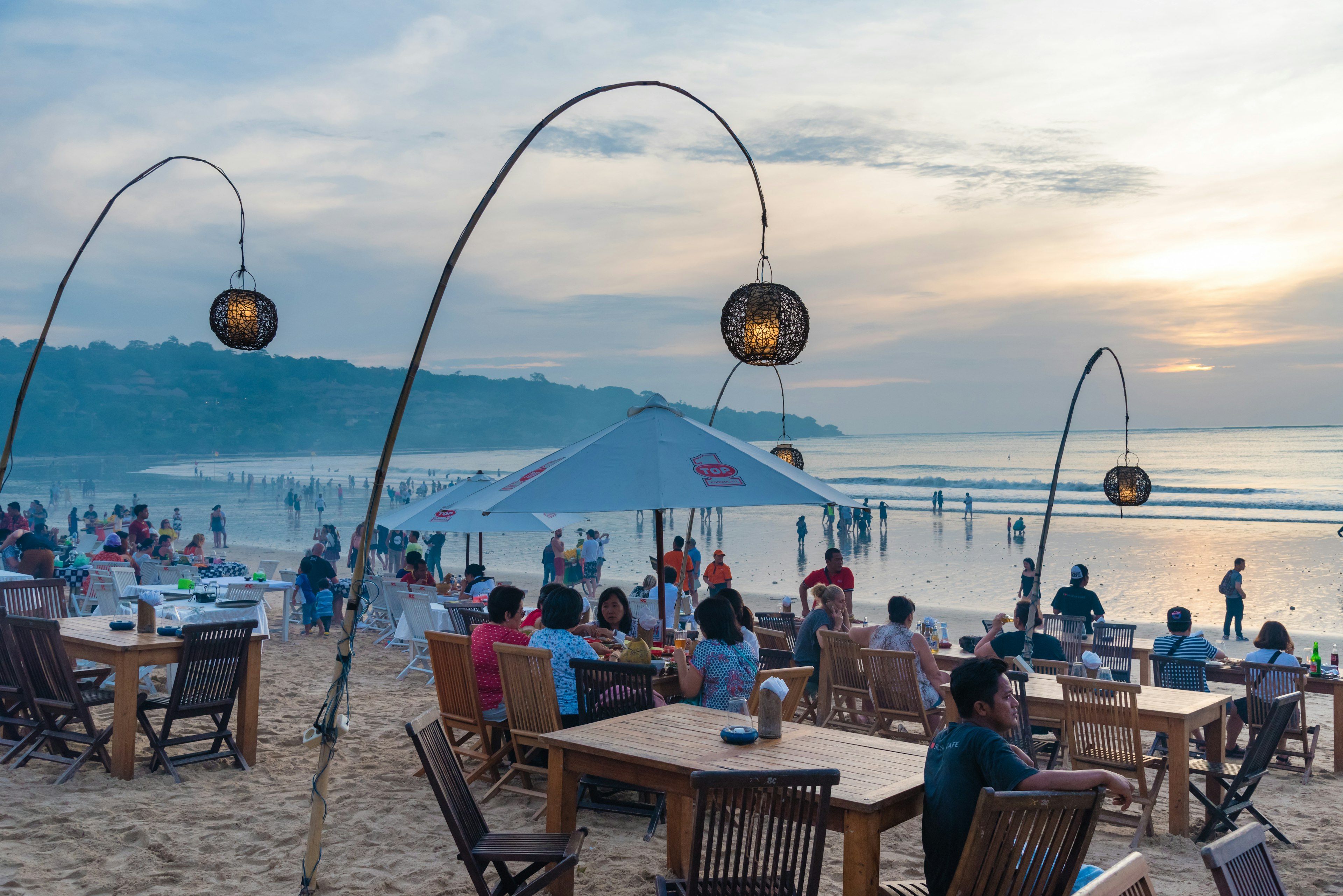 People seated on tables outside a restaurant at Jimbaran Beach in Bali, Indonesia