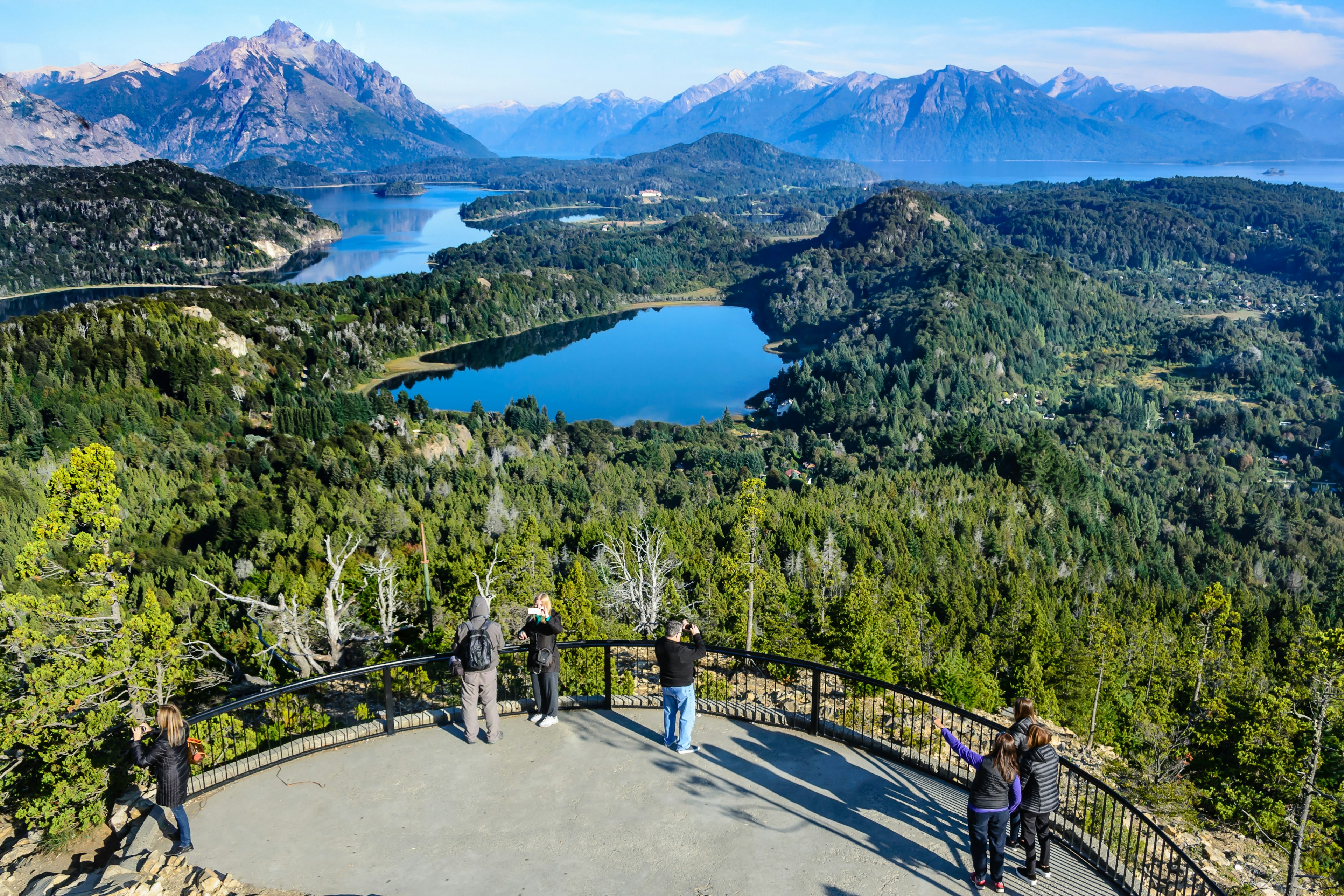 People looking over lakes, woodland and mountains from a viewpoint