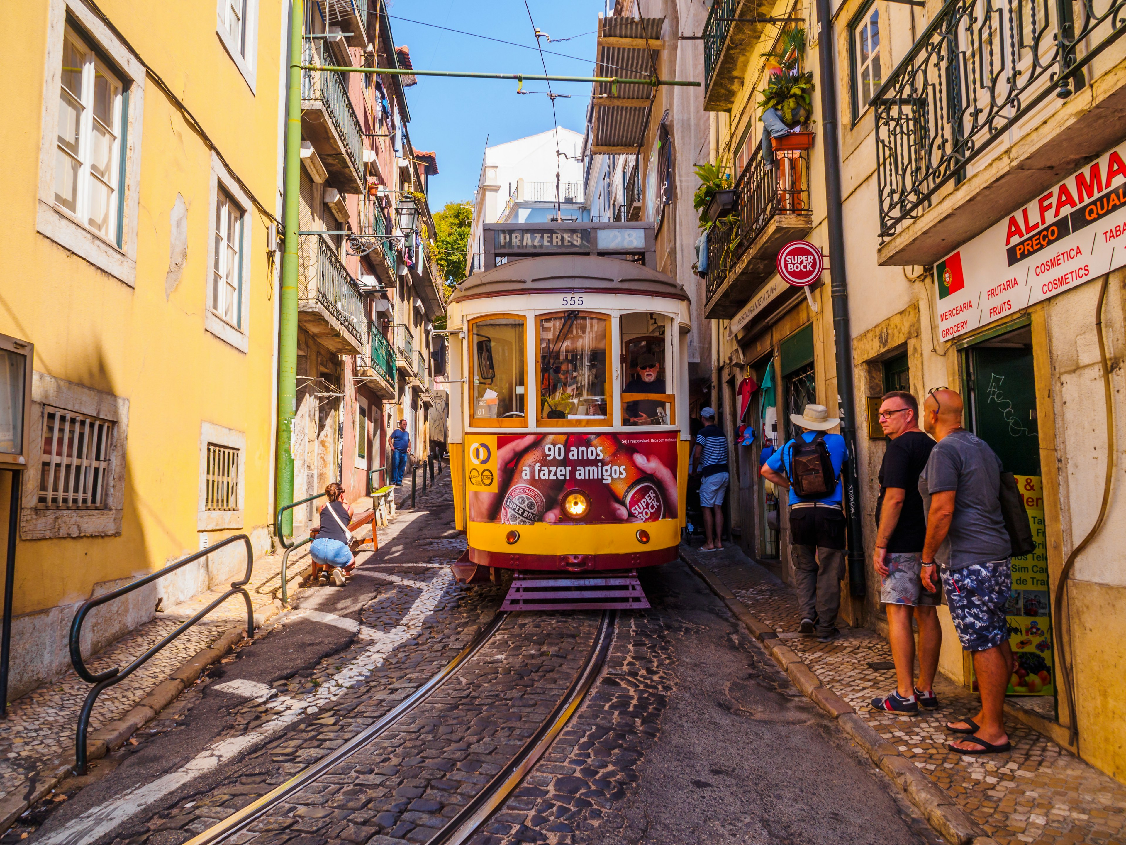August 22, 2017: People stepping to the sidewalk in order to let the street car pass in the streets of Lisbon.