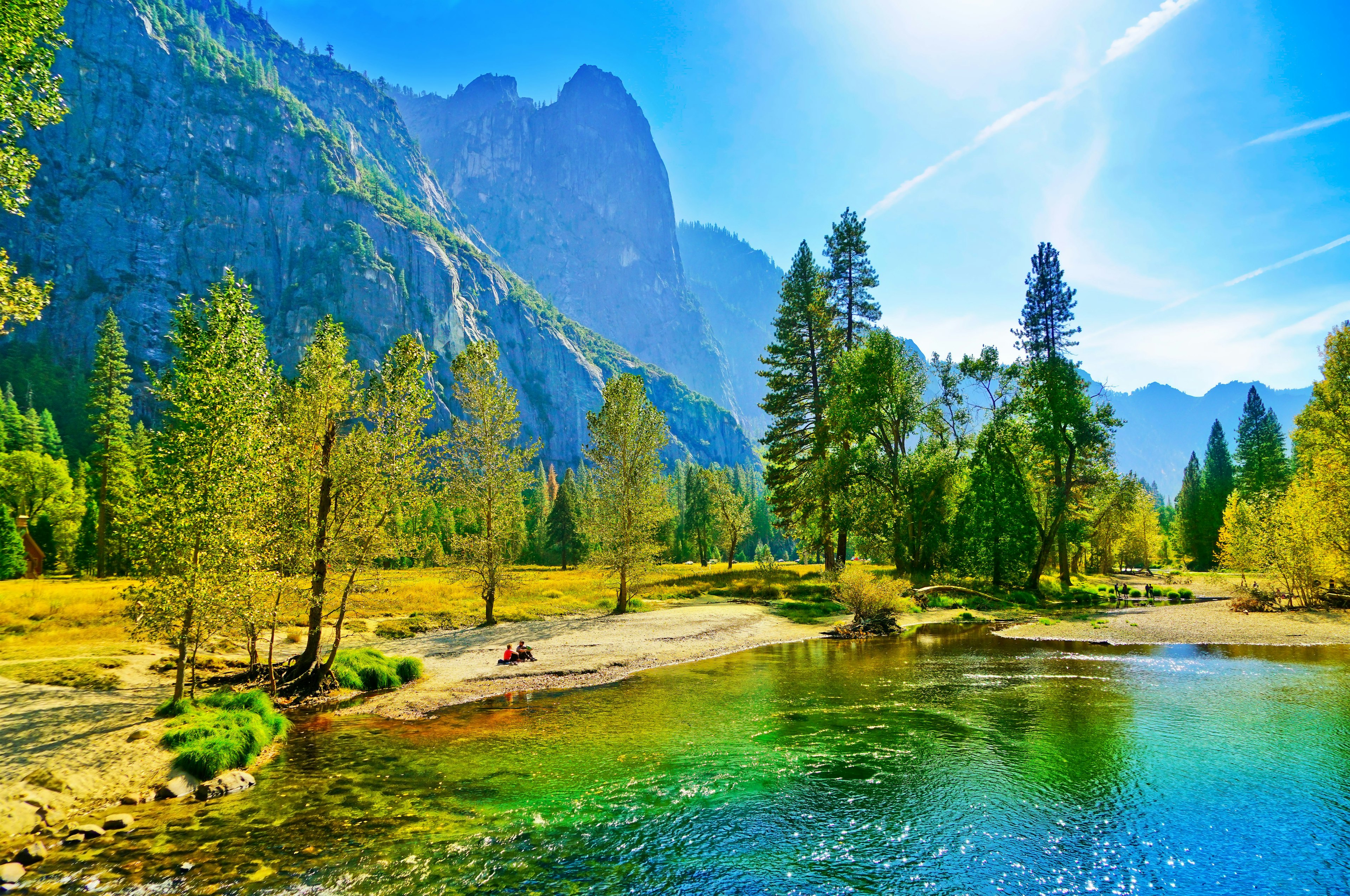 People sit on the banks of the Merced river in the Yosemite Valley during autumn.