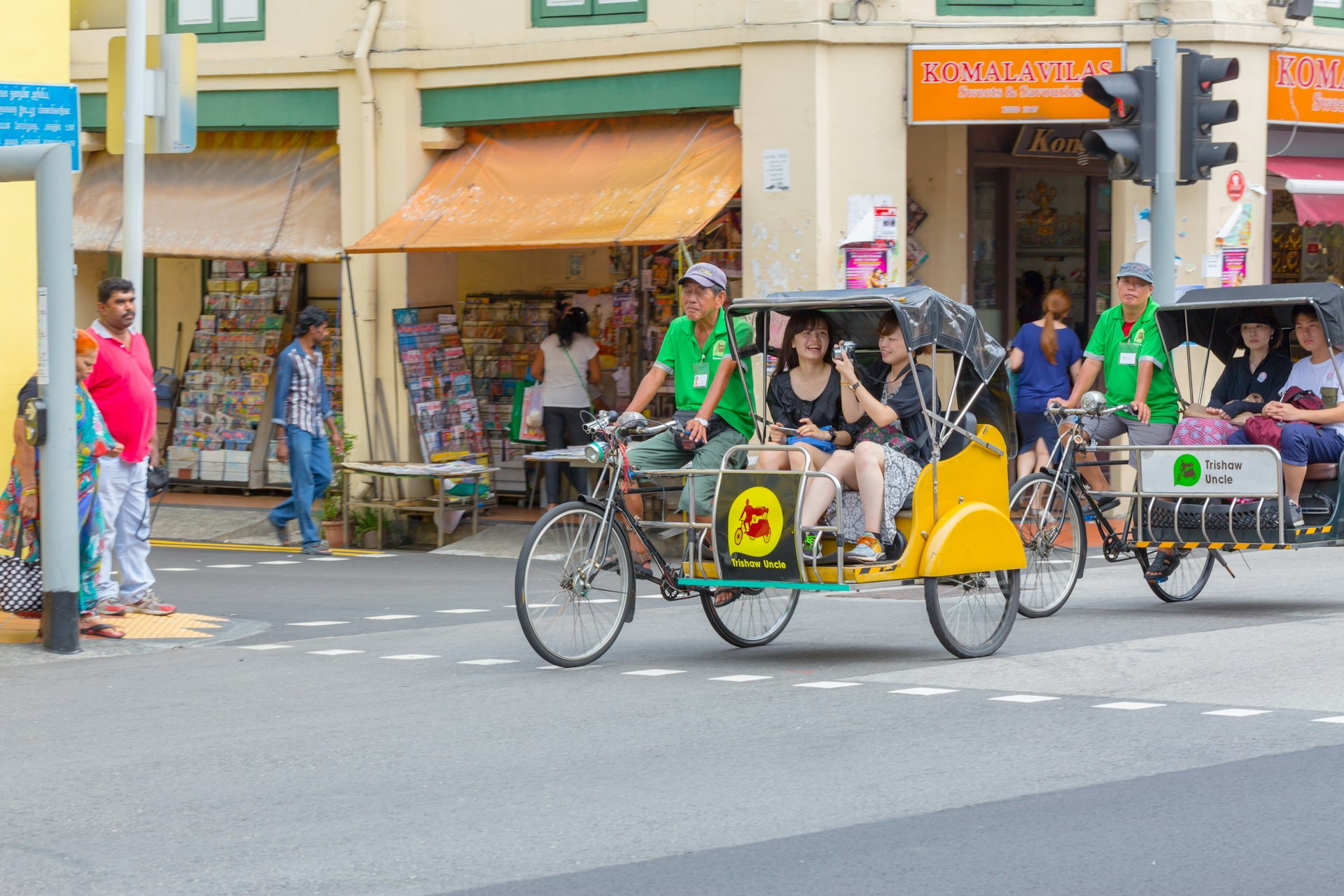 Couples ride on traditional Trishaw Uncle bikes on a Singapore street. 