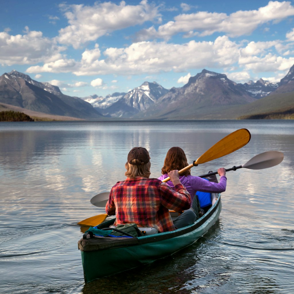 Adventurous traveling couple rowing a boat in a national park in Montana