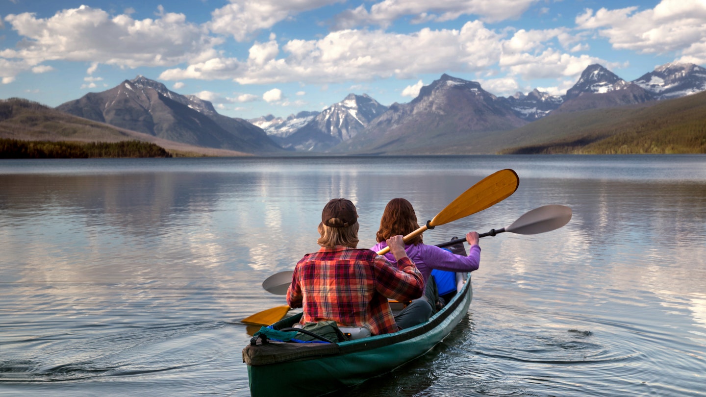 Adventurous traveling couple rowing a boat in a national park in Montana