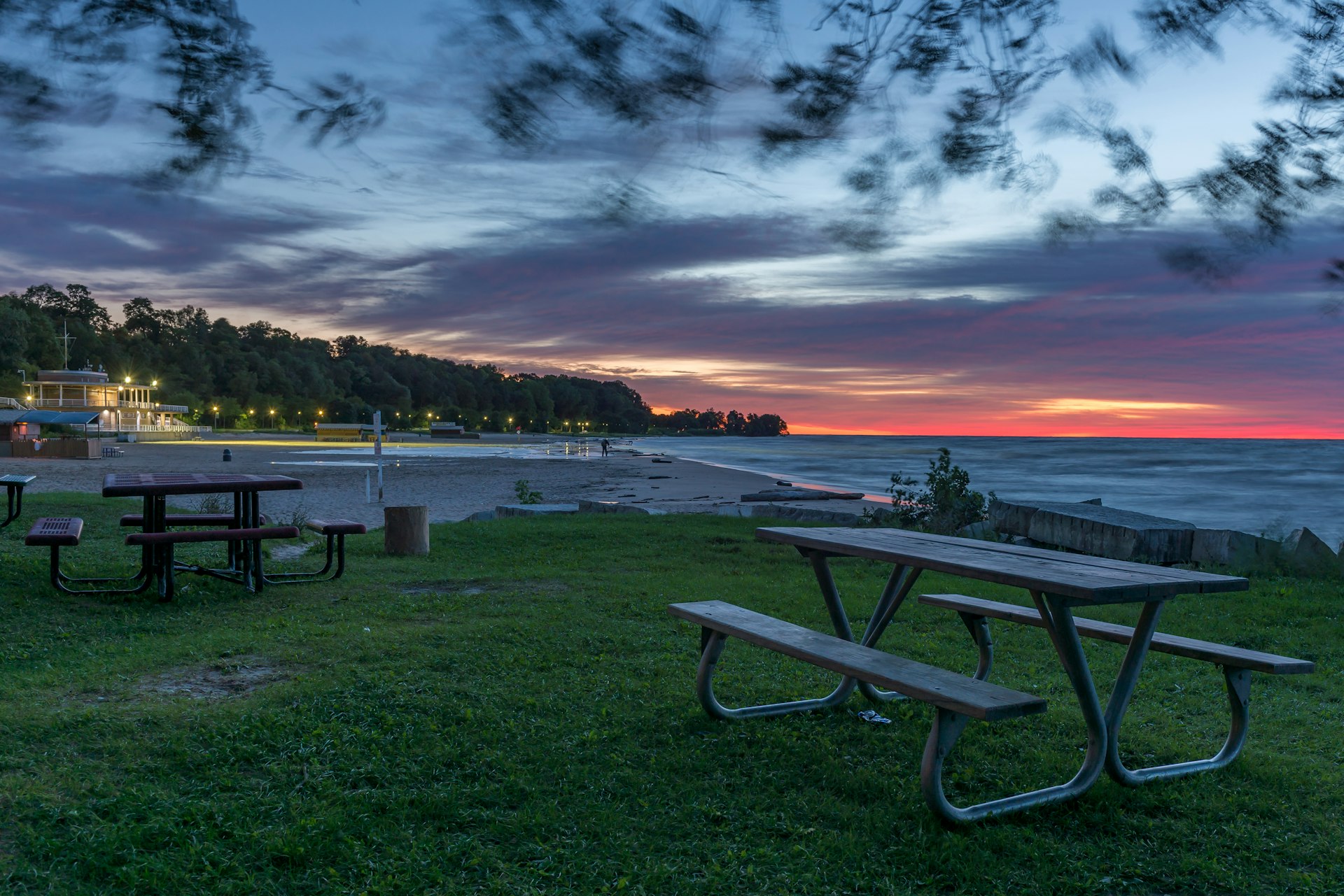 The sun rises over a beach lined with picnic benches