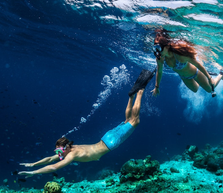 Young couple snorkeling and do skin diving on the coral reef edge in tropical waters of the Maldives