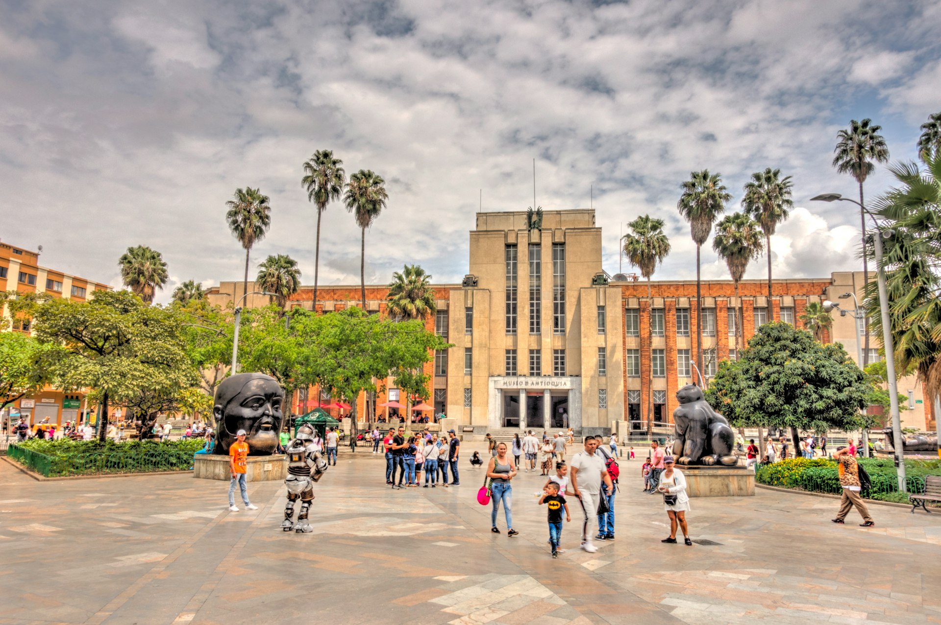 A large central square with huge bronze figurative sculptures backed by a large art gallery