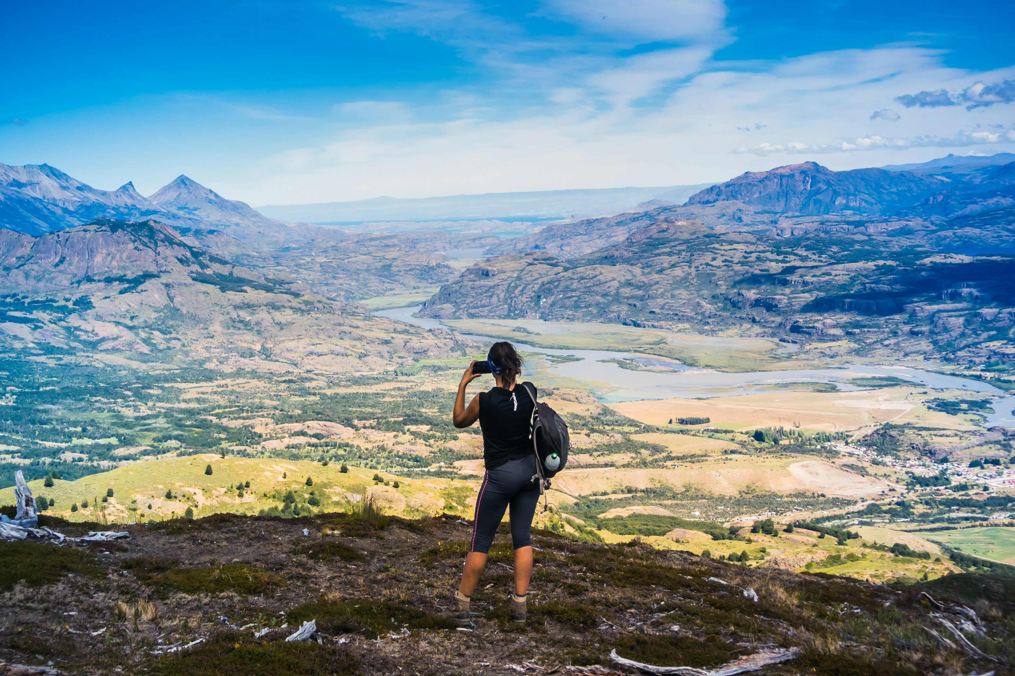 A hiker takes a picture of a vast mountainous landscape and river valley in Cerro Castillo, Chile