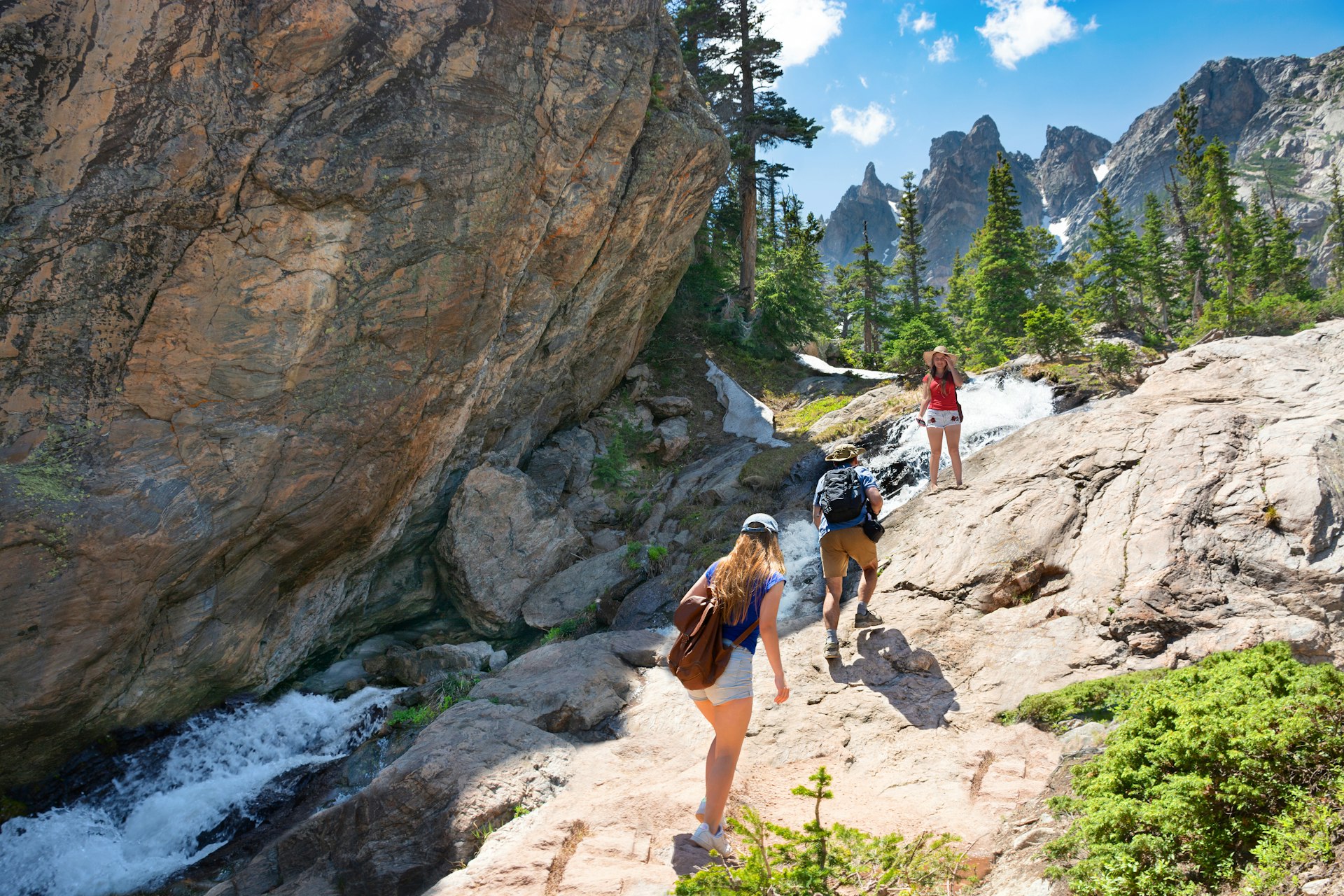 Hikers traverse a rocky stream in Rocky Mountain National Park