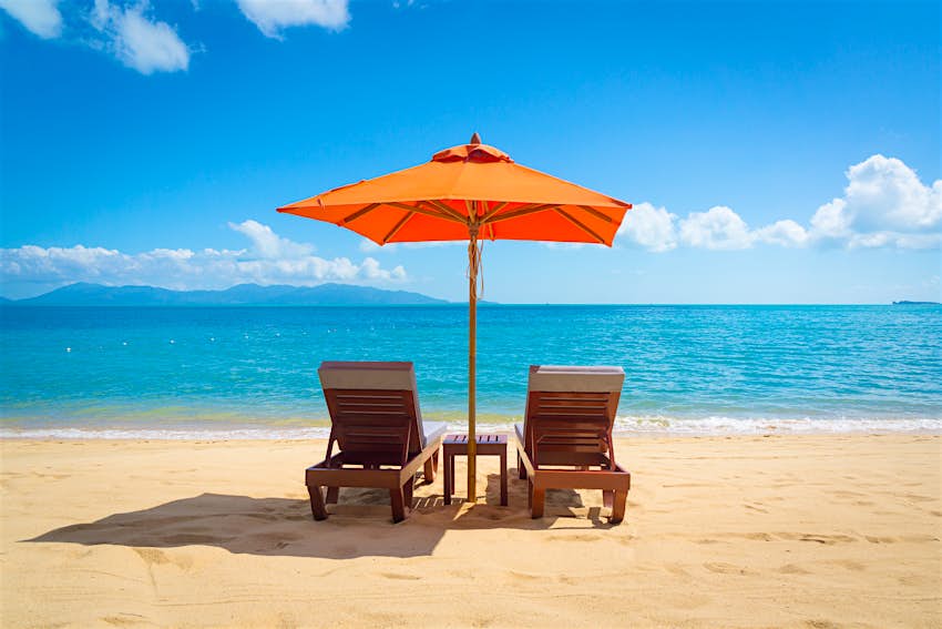 Two lounge chairs with sun umbrella on a beach